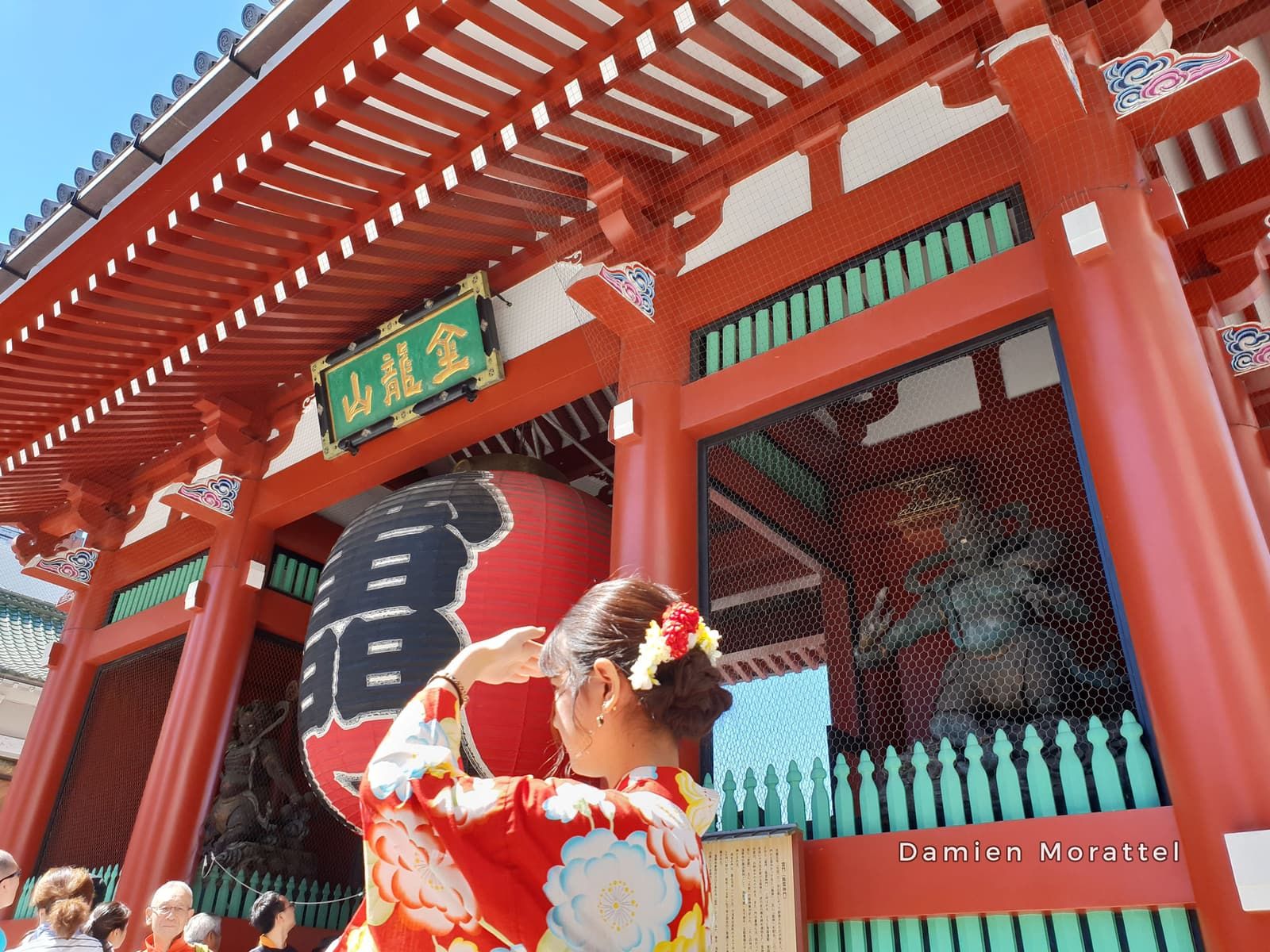 A large red lantern under a temple gate, a woman in a red kimono
