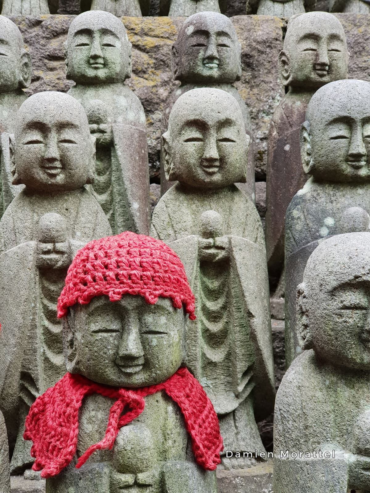 Stone statues, one wearing a knitted red hat