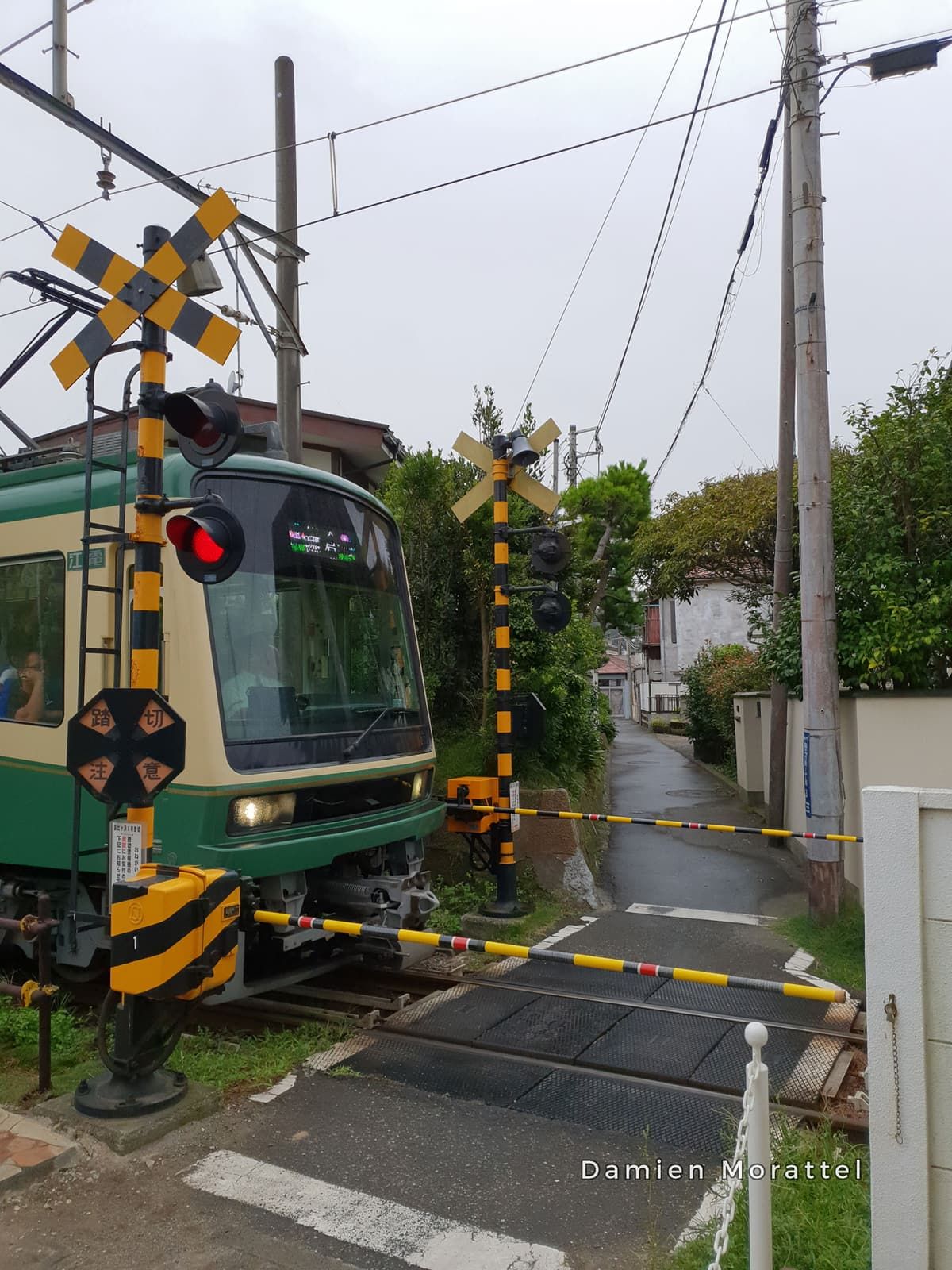 A small green train at a level crossing