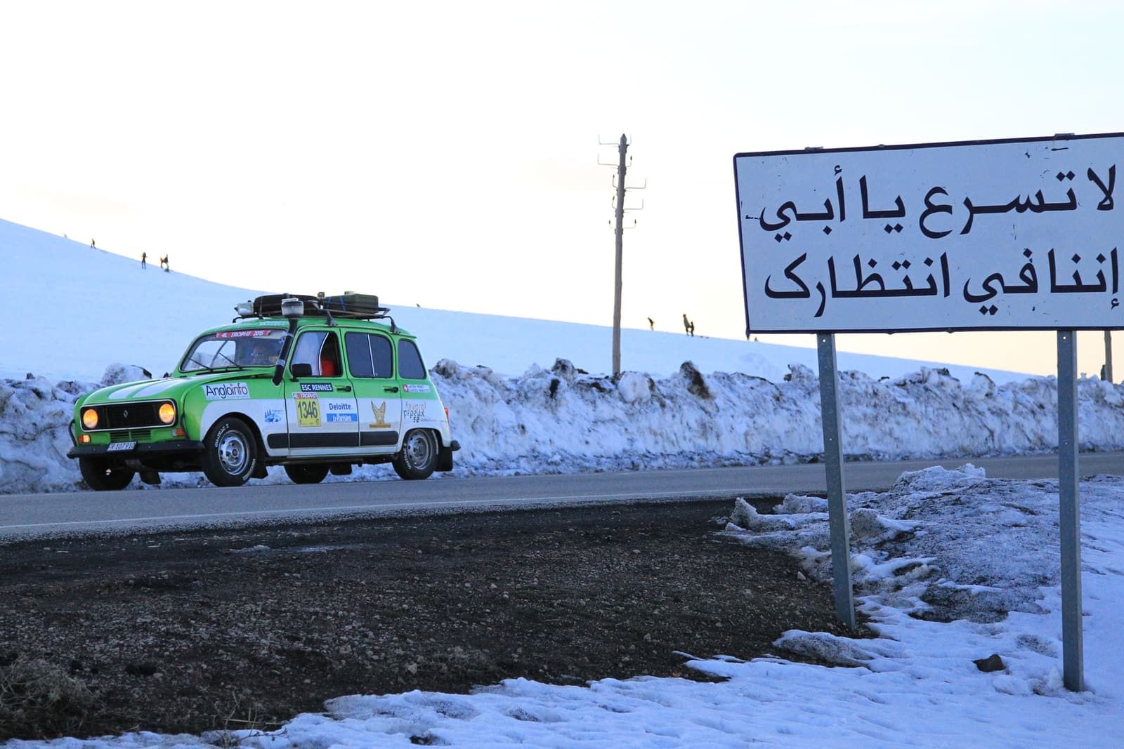The Renault 4 on a snowy road, next to a sign in Arabic