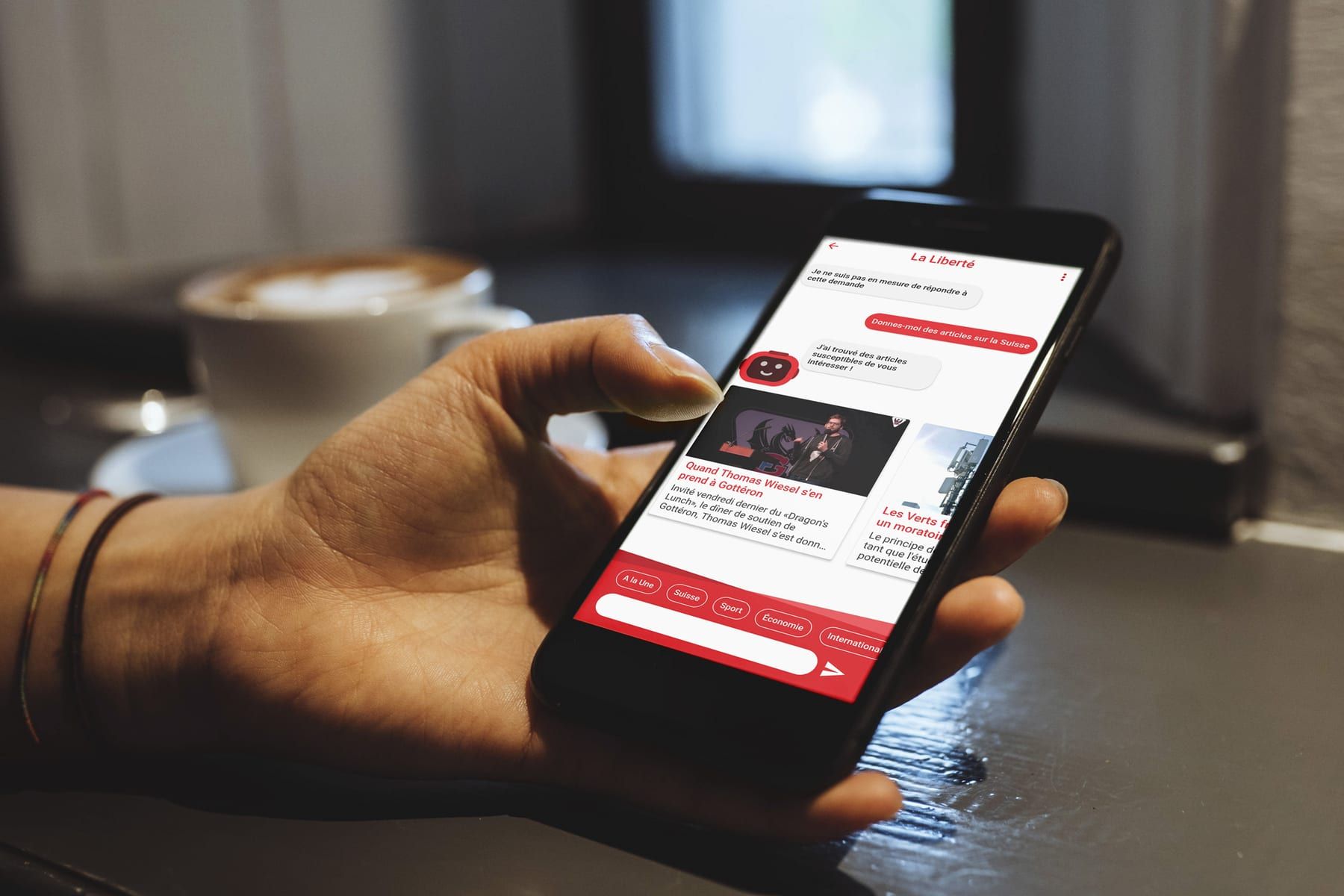A hand holding a phone showing a conversation with La Liberté's bot.